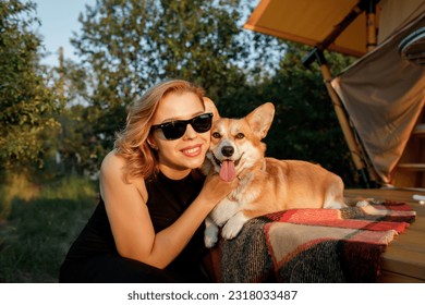 Happy young woman with Welsh Corgi Pembroke dog relaxing in glamping on summer day. Luxury camping tent for outdoor recreation and recreation. Lifestyle concept - Powered by Shutterstock