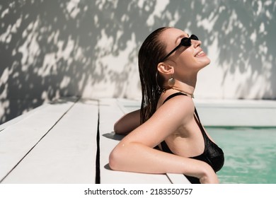 happy young woman with wet hair and stylish sunglasses sunbathing in pool - Powered by Shutterstock