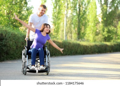 Happy young woman in wheelchair and her husband outdoors - Powered by Shutterstock