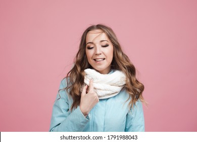 Happy Young Woman In A Winter Jacket And Scarf, Hair In The Wind. Portrait On A Pink Background