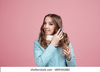 Happy Young Woman In A Winter Jacket And Scarf, Hair In The Wind. Portrait On A Pink Background