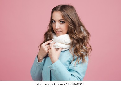 Happy Young Woman In A Winter Jacket And Scarf, Hair In The Wind. Portrait On A Pink Background