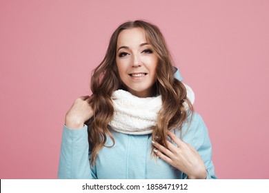 Happy Young Woman In A Winter Jacket And Scarf, Hair In The Wind. Portrait On A Pink Background