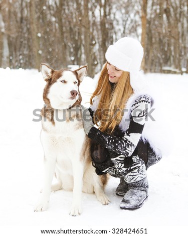 Happy young woman in the winter park with huskies dog