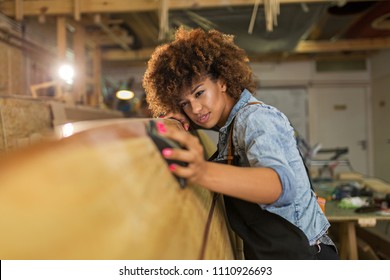 Happy young woman working on surfboard in her workshop
 - Powered by Shutterstock