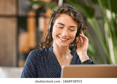 Happy young woman working on laptop while talking to customer on phone. Consulting corporate client in conversation with customer using computer. Service desk consultant talking in a call center. - Shutterstock ID 1868918953