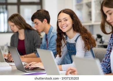 Happy young woman working on laptop and looking at camera in classroom. Portrait of smiling university student in library use computer for a research. Satisfied college student looking at camera. - Shutterstock ID 1937135203