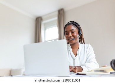 Happy Young Woman Working On Laptop While Talking To Customer On Phone. Consulting Corporate Client In Conversation With Customer Using Computer. Service Desk Consultant Talking In A Call Center.