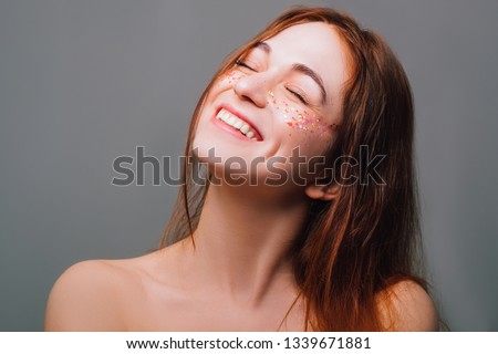 Happy young woman. Youth freedom. Beautiful redhead female. Closed eyes and toothy smile. Glitter freckles.