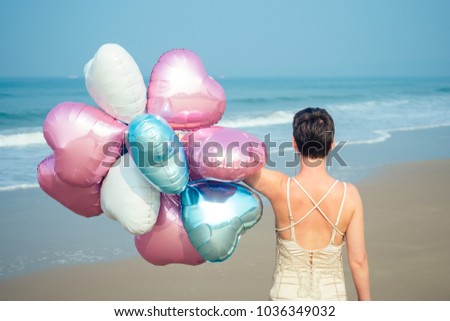 happy and young women exists with short hair holding a brighter and brilliant air balloons. bright balls in the hands of a girl resting on the beach