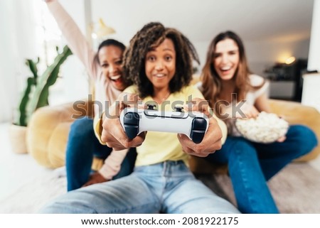 Happy young women having fun playing video games at home - Diverse girls entertaining in the living room with modern technologies - Happy lifestyle and gaming concept