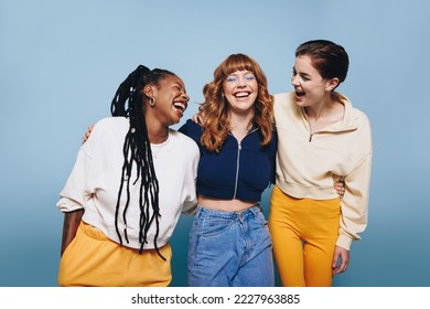 Happy young women laughing together in a studio. Group of female friends having fun while standing together. - Powered by Shutterstock