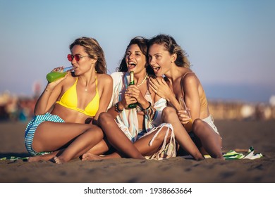 Happy Young Women Sitting On The Beach. Group Of Friends Enjoying On Beach Holiday.