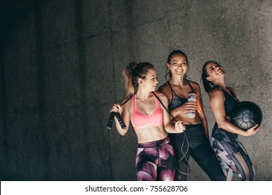 Happy Young Women Standing Together And Smiling After Exercising. Group Of Female Friends Relaxing After Workout Outdoors.