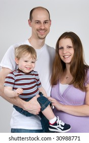 A Happy Young Working-class Family Poses For An Informal Portrait.