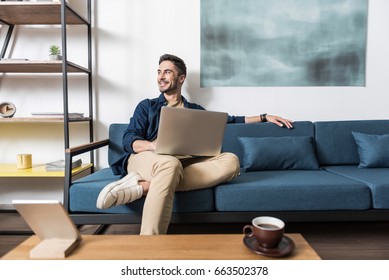 Happy youthful guy working at home via computer