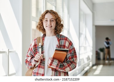 Happy Youthful Student In Casualwear Holding Books And Backpack And Looking At Camera While Standing In Corridor Of College At Break