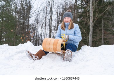 Happy/excited Teen Girl Sitting On A Wood Toboggan/sled At The Edge Of Snow Covered Hill In A Park.