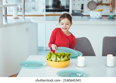 Happylittle Girl Setting The Table For Family Lunch During Holidays. Girl Setting Table. Preschooler Kid Helping Mother To Set Table In Kitchen.