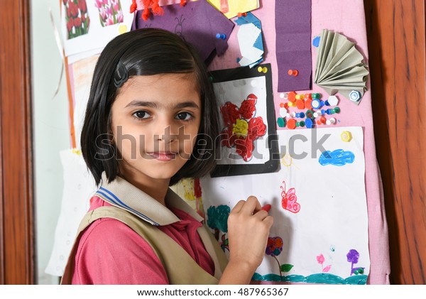 Happy/smiling Indian school girl/kid/student learning/drawing
