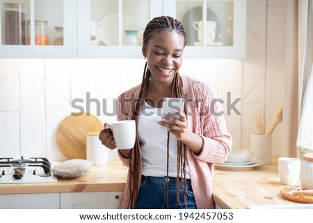 Hapy Black Lady Drinking Morning Coffee And Using Smartphone In Kitchen