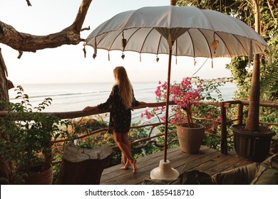 Hapy tourist wom stand  at the bar and enjoys the view of the endless blue sea and blue sky, Bali, Indonesia. Girl admires the view of the sea on the island of Bali