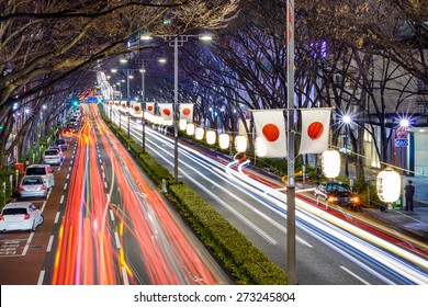 Harajuku, Tokyo, Japan traffic flows below Japanese flags at night. 