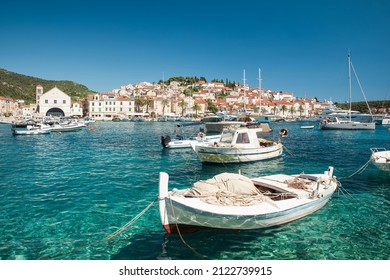 Harbor with boats in turquoise waters on island Hvar, Croatia with old town on background. Touristic resort. Summer vacation destination