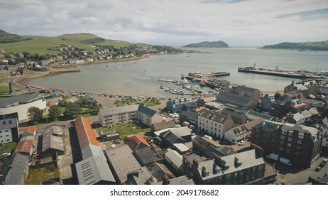 Harbor town cityscape aerial. Seascape with yachts, ships at urban street with road. Cars drive at traffic highway. Modern buildings at ocean shore of Campbeltown, Scotland, Europe rise-up drone shot - Shutterstock ID 2049178682