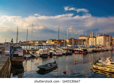 Harbour of Piran, Slovenia. Yachts and boats under picturesque sky. Piran is a popular sea resort on Adriatic coast. Guidepost wit Slovenian, Italian, English and German inscription 'Warning'