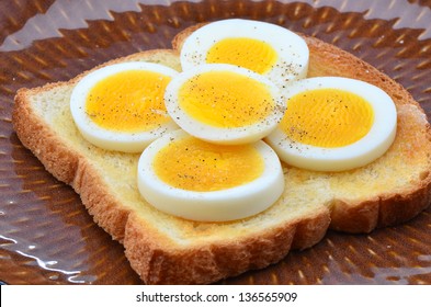 Hard Boiled Egg Slices On White Toast Sprinkled With Salt And Pepper