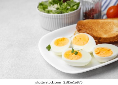 Hard boiled eggs with bread on light table, closeup. Space for text