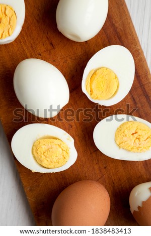 Hard Boiled Eggs on a rustic wooden board on a white wooden surface, top view. Flat lay, overhead, from above. Close-up.