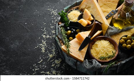 Hard cheese with olives and cheese knife on black stone background. Parmesan. Top view. Free space for your text.