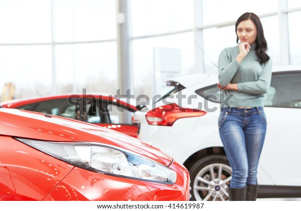 Hard choice. Selective focus on a car young\
woman choosing a new auto at the car\
salon
