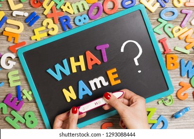 Hard to choose or decide the name of new born baby, with “what name“ question on blackboard and woman’s hand holding positive pregnancy test
