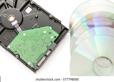 Hard disk drive (HDD) with circuit board and dvd discs on white background