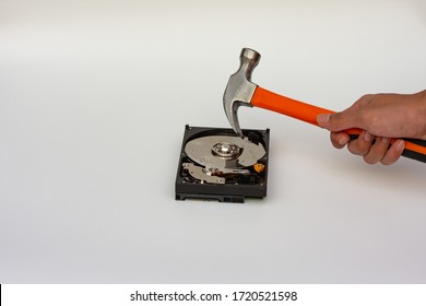 Hard disk drive platter being destroyed with a hammer on a white background.