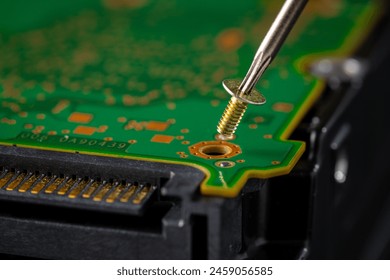 Hard disk drive and printed circuit board with SATA power connector. Magnetic driver torx bit and small machine screw on dark background. - Powered by Shutterstock