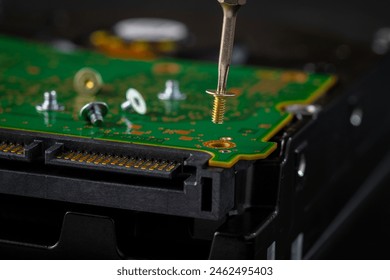 Hard disk drive and printed circuit board with SATA power connector. Magnetic driver torx bit and small machine screw on dark background. - Powered by Shutterstock