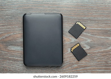 Hard disk drive and SD memory cards on grey wooden table, flat lay