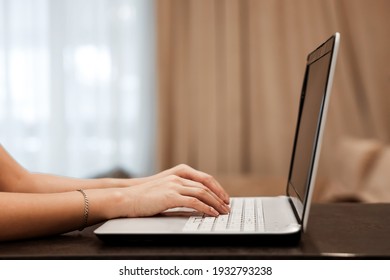 The hard hands of a businessman are typing on a laptop keyboard against the background of a blurred room. Concept for workplace, office, coworking, business, finance