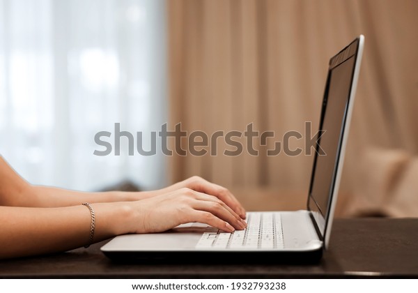 The hard hands of a\
businessman are typing on a laptop keyboard against the background\
of a blurred room. Concept for workplace, office, coworking,\
business, finance