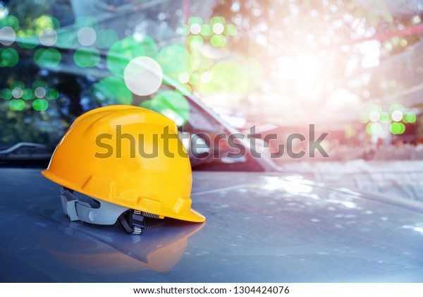 hard hat safety helmet in\
construction site on car with bokeh background for safety\
concept.