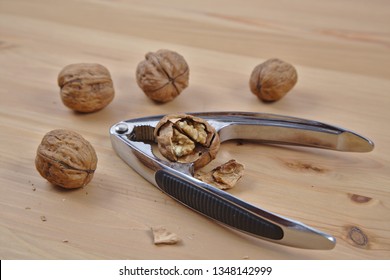 It's a hard nut to crack. 4 walnuts arranged around a walnut with cracked shell and a nutcracker.