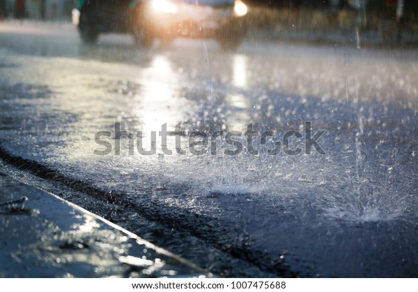 Hard rain fall at night with blurry cars as\
background.Selective\
focus.