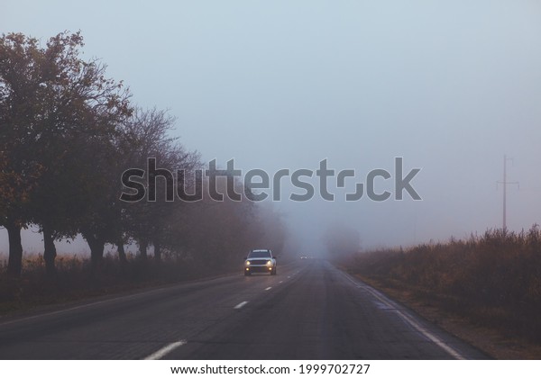 Hard road in the foggy morning . Cars on the highway in\
the fog 