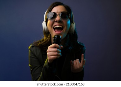 Hard Rock Music. Close Up Of An Attractive Female Singer With Headphones Making The Rock And Roll Sign While Singing 