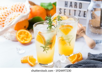 Hard Seltzer Cocktail With Orange, Rosemary And Ice On A Table. Summer Refreshing Beverage, Drink On A White Table