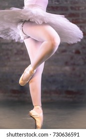 Hard work ballet technique exercise. Closeup of young attractive girls body in white balletic tulle skirt, panties and lace pointe shoes. Motion blur of elegant ballerina dancer legs.
